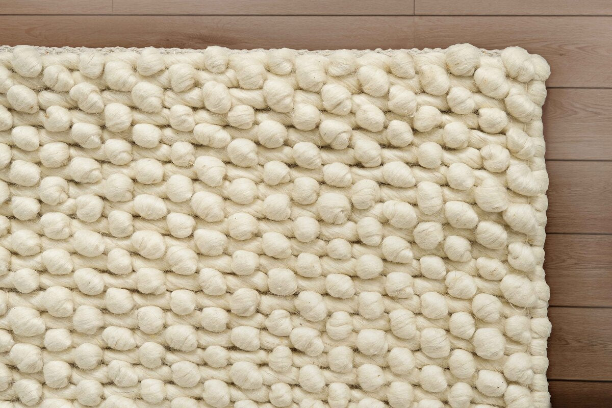 Mat for drawing room with textured ivory rug on a wooden floor