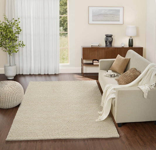 Mat for drawing room with a ivory rug, white sofa, and wooden side table.
